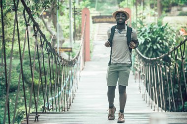 Afrikalı gezgin köprüde gülümseyerek ve mutlu bir şekilde duruyor.