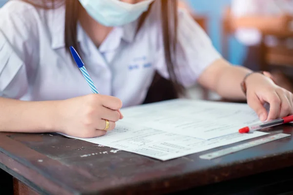 Covid-19 'u korumak için yüz maskesi takan öğrenciler ve stresten sınıfta muayene oluyorlar.