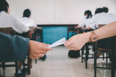 Öğrenciler ders sırasında birbirlerine gizlice notlar veriyorlar.