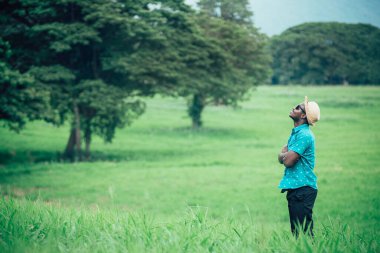 Afrikalı gezgin yeşil çayırlar arasında mutlu bir gülümsemeyle duruyor.
