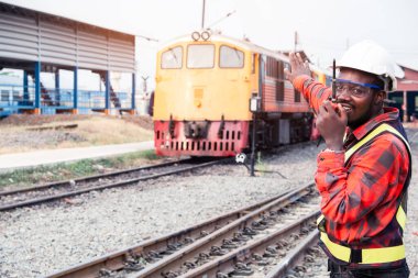 Afrikalı mühendis, telsiz ya da telsizle konuşarak treni kontrol etmek için elini kaldırdı.