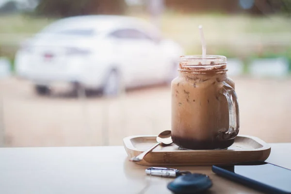 Ice coffee Key and smart phone in cafe with car parked in background