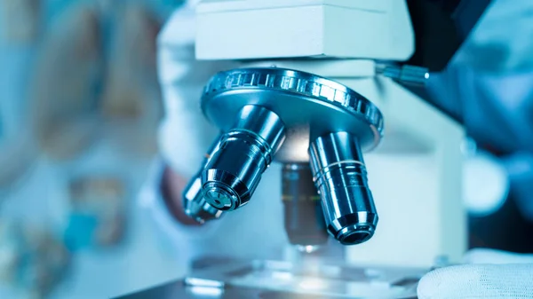 Doktor mikroskopta bilimsel laboratuvarda tıbbî araştırma covid-19 üzerinde çalışırken...