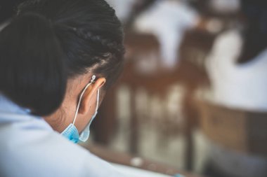 Covid-19 'u korumak için maske takan öğrenciler ve stresten sınıfta muayene oluyorlar.