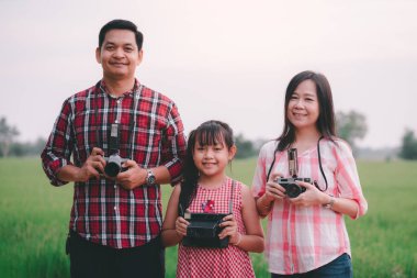 Eski Asyalı fotoğrafçı ailesi fotoğraf makinesiyle mutlu mesut fotoğraf çekiyor.