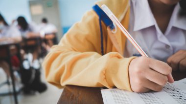 Sınav sorularını yazan ve okuyan öğrenciler, okuldaki sınav kağıtlarını stres ile okuyorlar.