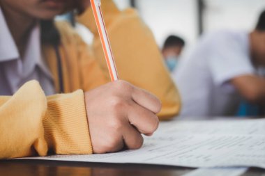 Sınav sorularını yazan ve okuyan öğrenciler, okuldaki sınav kağıtlarını stres ile okuyorlar.