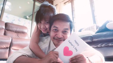 Babası yatmış ve kızının evde verdiği kartpostalı okuyordu. Mutlu Babalar Günü kavramı.