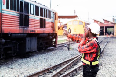 Afrikalı mühendis, telsiz ya da telsizle konuşarak treni kontrol etmek için elini kaldırdı.