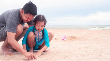 Mutlu baba-kız kumsalda kum yığınları yapıyor. Babalar Günü kavramı.