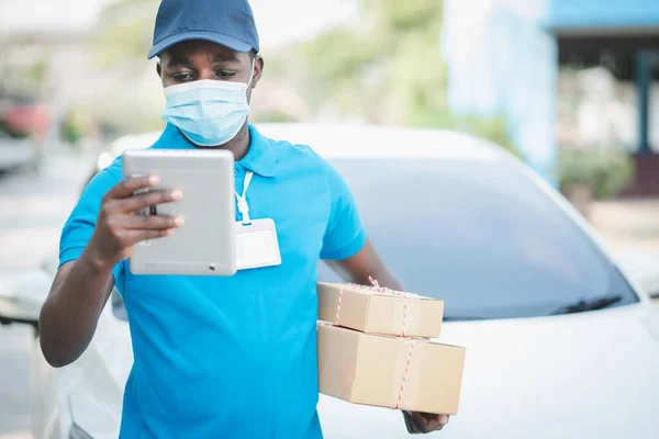 Africano Homem Entrega Usando Máscara Facial Olhando Tablet Com Segurando — Fotografia de Stock