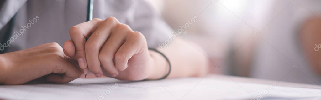 Close up to students writing and reading exam answer sheets exercises in classroom of school with stress