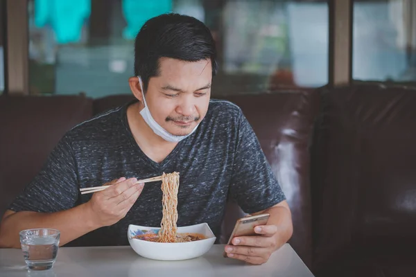 Hombre Comiendo Fideos Usando Smartphone Casa Durante Bloqueo Debido Situación —  Fotos de Stock