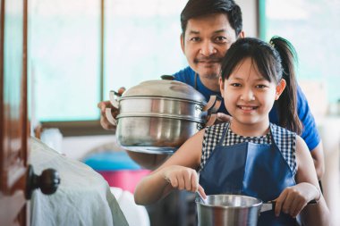 Baba ve kız mutfakta mutlu bir şekilde yemek pişiriyorlar. Aile yemekleri konsepti