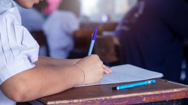 Sınav sorularını yazan ve okuyan öğrenciler, okuldaki sınav kağıtlarını stres ile okuyorlar.