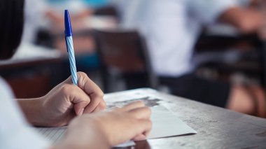 Sınav sorularını yazan ve okuyan öğrenciler, okuldaki sınav kağıtlarını stres ile okuyorlar.