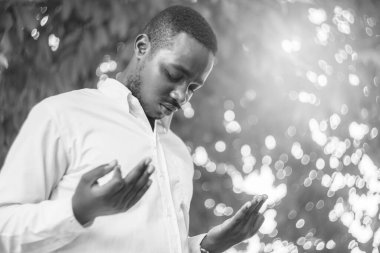 Afrikalı adam Tanrı 'ya dua ediyor. Işıklı ve güzel bir bokeh ile siyah-beyaz tarzıyla.