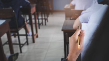 Sınav sorularını yazan ve okuyan öğrenciler, okuldaki sınav kağıtlarını stres ile okuyorlar.