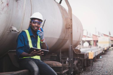 Trenin tamiri için kask, koruluk ve güvenlik yeleği giyen Afrikalı makine mühendisi.