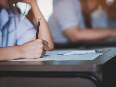 Öğrenciler sınav cevap kağıtlarını baş ağrısı ve stres ile birlikte okul sınıfında okuyorlar.