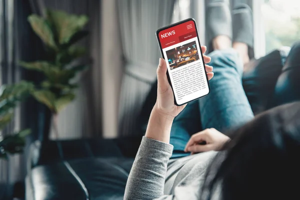 Akıllı telefondan online haberler. Model web sitesi. Evde cep telefonu ekran uygulamasında haber ya da makale okuyan bir kadın. Gazete ve internet portalı.