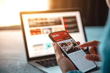 Akıllı telefondan online haberler. Model web sitesi. Evde cep telefonu ekran uygulamasında haber ya da makale okuyan bir kadın. Gazete ve internet portalı.