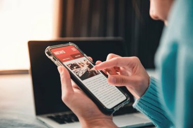 Akıllı telefondan online haberler. Model web sitesi. Evde cep telefonu ekran uygulamasında haber ya da makale okuyan bir kadın. Gazete ve internet portalı.