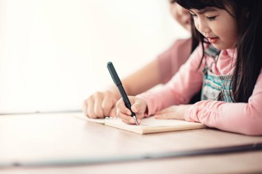 Kapalı kapılar ardında annesinin olduğu bir not defterine yazan bir çocuk. Boşluğu kopyala.