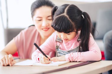 Kapalı kapılar ardında annesinin olduğu bir not defterine yazan çocuğun elleri..