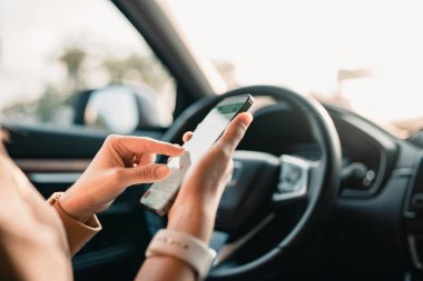 Araba kullanan ve uygulama navigasyon haritası kullanarak akıllı telefon tutan kadına yakın çekim.