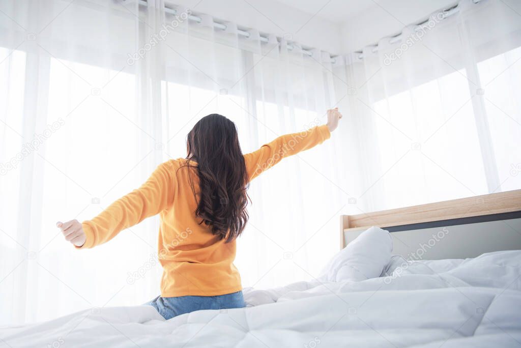 Woman stretching hands in bed after wake up in the morning, Concept of a new day and joyful weekend.