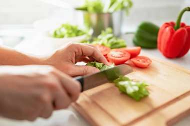 İnsan eli mutfakta yemek pişirir. Domates doğrayan kadın. Sağlıklı yemek ve vejetaryen gıda konsepti.