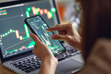 Yakın plan - Kadın akıllı telefon, kripto para birimi gelecekteki fiyat öngörüsünde Bitcoin fiyat tablosunu kontrol ediyor.