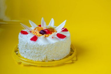 Sarı arka planda jöleli beyaz bir pasta.
