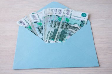 Masanın üzerinde, üzerinde Rus banknotları olan bin ruble değerinde mavi bir zarf var.