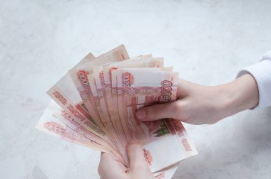 Kadınların elleri masanın üzerinde beş bin ruble tomar para tutuyor.