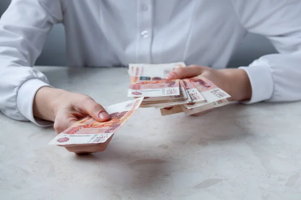 Masada beyaz gömlekli bir kız elinde büyük para kavramını tutuyor.