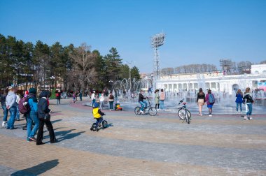 Rusya, Khabarovsk, 1 Mayıs 2018: İnsanlar Khabarovsk şehrinin eğlence parkında yaya ışık dinamik çeşmesinde yürüyorlar.