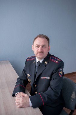 Masada polis üniforması giymiş bıyıklı bir adamın portresi