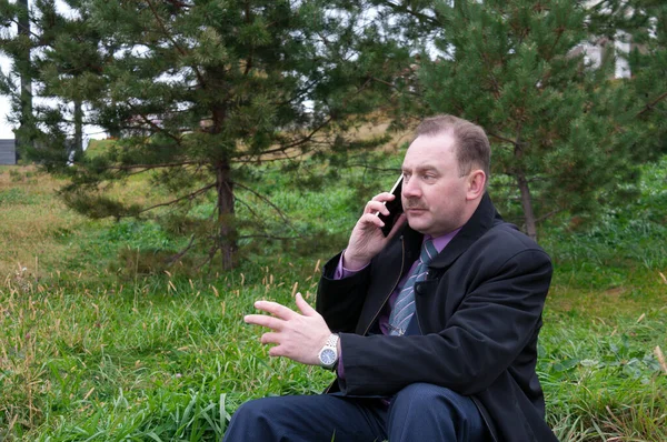 Чоловік Сидить Траві Розмовляючи Телефону Жестикулюючи Руками — стокове фото