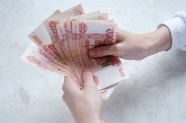 Kadınların elleri masanın üzerinde beş bin ruble tomar para tutuyor.