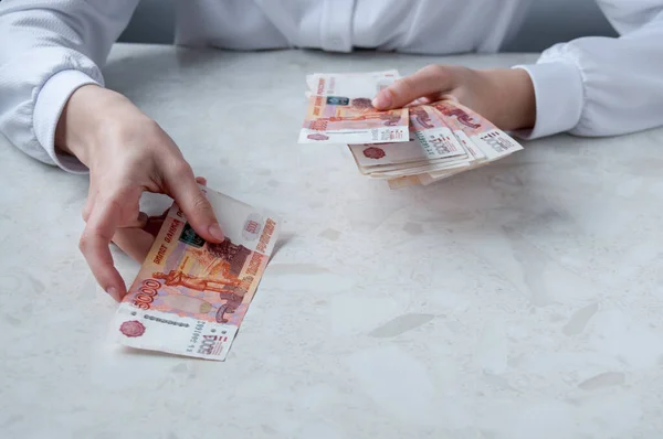 Masadaki beyaz gömlekli bir kız para sayıyor, bir banka çalışanı.