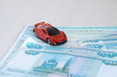 Rus sigorta direği ve kağıt rubledeki kırmızı araba modeli, yollardaki kazalara karşı sigorta kavramı.