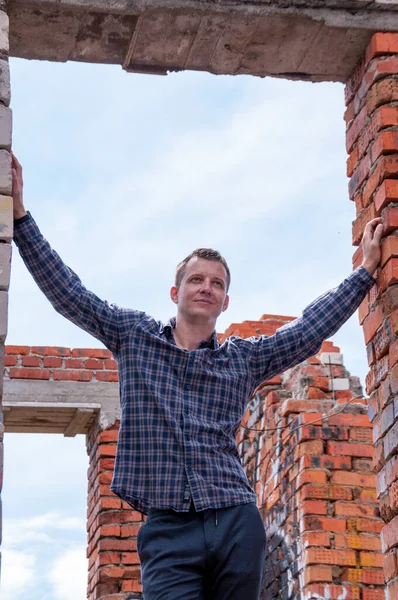 Portrait of a young man in a brick house under construction
