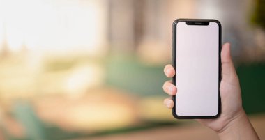 İnternette ya da internette bir şeyler bulmak için akıllı telefonu tutan bir kadın, aynı zamanda sosyal uzaklık kavramı için ortak çalışma alanında tek kişilik bir masada oturuyor..
