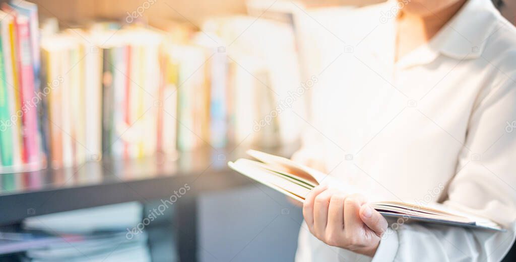 Female hand holding notebook with the space book for note or remark and sitting in the library for protect the Covid-19 with the social distancing concept.