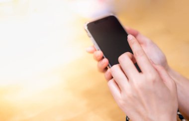 Cerrahi maske takan ve internetten ya da internetten bir şeyler almak için akıllı telefon tutan bir kadın, sosyal uzaklık kavramı için ortak çalışma alanında tek kişilik bir masada oturuyor..
