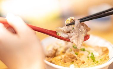 El, yemek çubukları ve kaşıkla sebzeli Japon eriştesi ve ahşap masada sigara içmek için Asya yemeği, abur cubur konsepti ve odaklanmayı seçer..