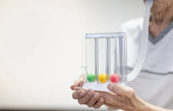 The old patient hand holding the Tri-ball incentive spirometry is medical equipment for post operation. The equipment for Lungs function testing & Pulmonary test.