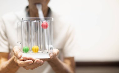 Üç Top 'u tutan yaşlı hasta spirometriyi ameliyat sonrası tıbbi ekipman olarak kullanıyor. Ciğerlerin fonksiyon testi ve akciğer testi ekipmanları.